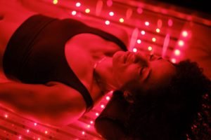 A multiracial woman on an LED light bed, receiving red light therapy. A multiracial woman on an LED light bed, receiving red light therapy.