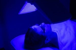 terapia-luz-ultravioleta Young woman having blue LED light facial therapy treatment in beauty salon. Beauty and wellness concept